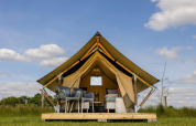 Tienda safari en CharmeCamping De Regge-Vallei, Holanda, equipada con muebles modernos y vistas naturales.