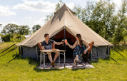 Dos personas disfrutan de una comida junto a una tienda glamping en CharmeCamping De Regge-Vallei, Países Bajos.