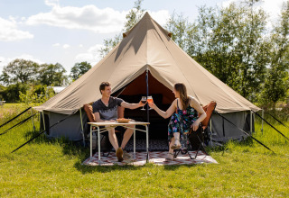 Twee mensen genieten van een maaltijd bij een glamping belltent op CharmeCamping De Regge-Vallei, Nederland.