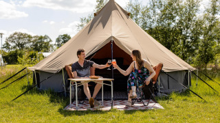 Twee personen genieten van een maaltijd bij een glamping belltent op CharmeCamping De Regge-Vallei, Nederland.