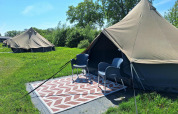 Tentes safari glamping avec chaises et tapis devant, sur l’herbe à CharmeCamping De Regge-Vallei, Pays-Bas.
