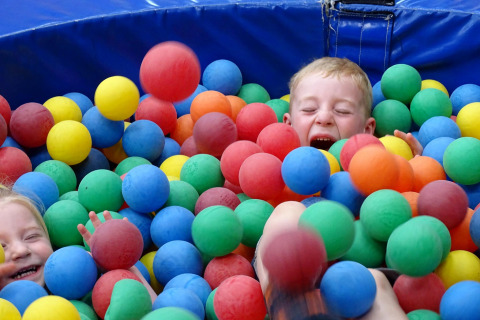 Deux enfants rient et jouent dans une piscine à balles colorées au Glamping belltent de CharmeCamping De Regge-Vallei.