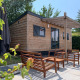 Træbeklædt tiny house med udendørs siddepladser i Holiday Park Mölke, Holland, omgivet af natur.