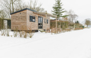 Petite maison en bois au Holiday Park Mölke aux Pays-Bas, entourée de neige et de paysage hivernal.