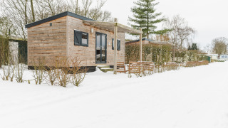 Pequeña casa de madera en Holiday Park Mölke, Países Bajos, rodeada de nieve y paisaje invernal.
