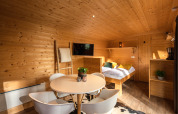 Intérieur d'une tiny house chaleureuse en bois avec table ronde et lit au Holiday Park Mölke.