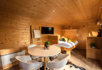 Indretning af et hyggeligt tiny house med træpaneler, spisebord og dobbeltseng på Holiday Park Mölke.