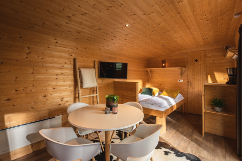 Interieur van een knus tiny house met houten wanden, ronde eettafel en bed in Holiday Park Mölke.