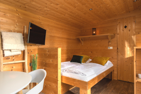 Interior de una acogedora Tiny House en Holiday Park Mölke, Países Bajos, con paredes de madera y cama moderna.