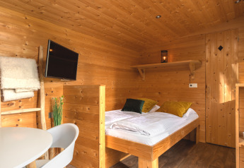 Binnenzicht van een gezellige Tiny House in Holiday Park Mölke, Nederland, met houten interieur en bed.