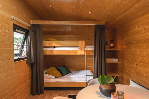 Interior de una tiny house en Holiday Park Mölke, Países Bajos, con literas y paredes de madera.