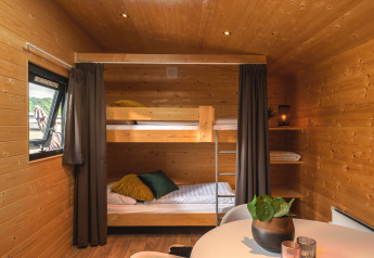 Interieur van een Tiny House bij Holiday Park Mölke, Nederland, met stapelbedden en houten muren.