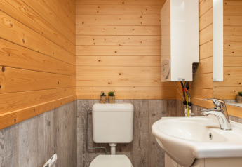 Kleine badkamer in een tiny house met houten bekleding, wit toilet en lavabo, Tiny House in Nederland.