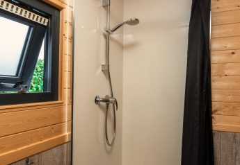 Moderne Duschkabine mit Fenster und Holzverkleidung in einem Tiny House im Holiday Park Mölke, Niederlande.