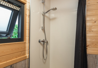 Moderne douche met raam en houten wandbekleding in een tiny house bij Holiday Park Mölke, Nederland.