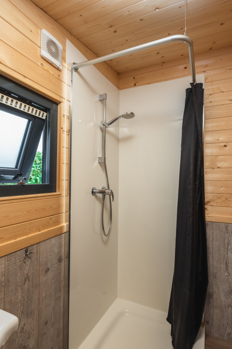 Douche moderne avec fenêtre et lambris bois dans une tiny house au Holiday Park Mölke, Pays-Bas.