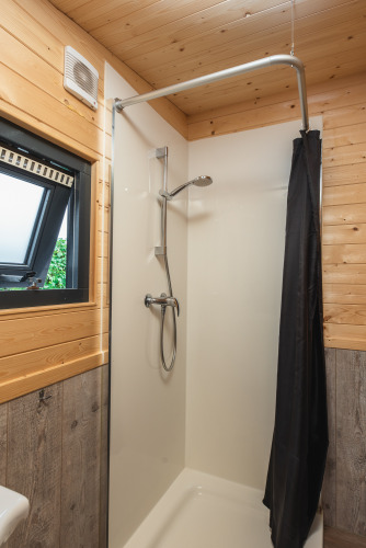 Moderne douche met raam en houten bekleding in een tiny house bij Holiday Park Mölke, Nederland.