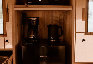 Kitchen area inside safari tent Groupaccommodation 'de Blokhut' with microwave, coffee maker, and fridge.