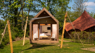 Kleine Boutique-Suite im Holiday Park Mölke, Niederlande, vor Bäumen, mit gemütlicher Terrasse.