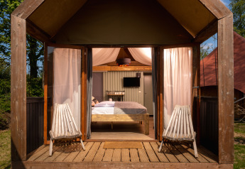 Boutique suite in Holiday Park Mölke in Nederland, klein huisje met tweepersoonsbed en stoelen buiten.
