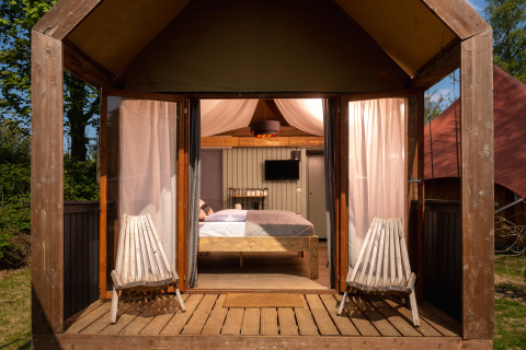 Boutique suite på Holiday Park Mölke i Nederlandene, lille træhus med dobbeltseng og stole udendørs.