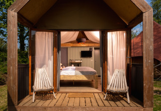 Boutique suite på Holiday Park Mölke i Nederlandene, lille træhus med dobbeltseng og stole udendørs.