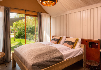 Knusse slaapkamer met tweepersoonsbed en grote ramen in een boutique suite bij Holiday Park Mölke, Nederland.