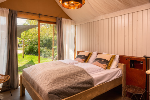 Hyggelig soveværelse med dobbeltseng og store vinduer i en boutique suite ved Holiday Park Mölke i Holland.