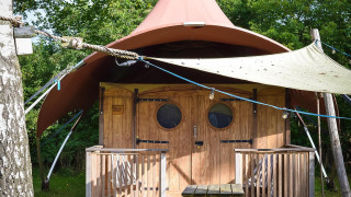 Foto eines Dream Suite Safari Zeltes im Holiday Park Mölke, Niederlande, mit Holzveranda und Sitzbank.
