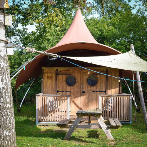 Foto de la tienda safari Dream Suite en Holiday Park Mölke, Países Bajos, con porche y banco de picnic exterior.