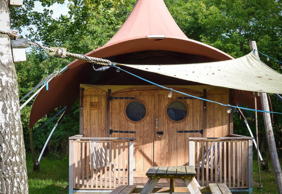 Foto della tenda safari Dream Suite all’Holiday Park Mölke nei Paesi Bassi con veranda e panchina da picnic.