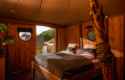 Schlafzimmer im Dream Suite Safari-Zelt im Holiday Park Mölke in den Niederlanden mit Holzmöbeln.