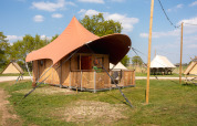 Safaritent Dream suite bij Holiday Park Mölke in Nederland, met veranda en groene, ruime omgeving.