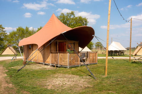 Safaritent Dream suite bij Holiday Park Mölke in Nederland, met veranda en groene, ruime omgeving.