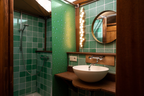 Baño en la tienda safari Dream suite en Holiday Park Mölke, Países Bajos, con azulejos verdes y lavabo redondo.