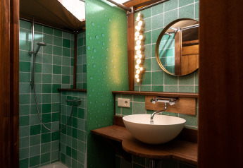 Baño en la tienda safari Dream suite en Holiday Park Mölke, Países Bajos, con azulejos verdes y lavabo redondo.