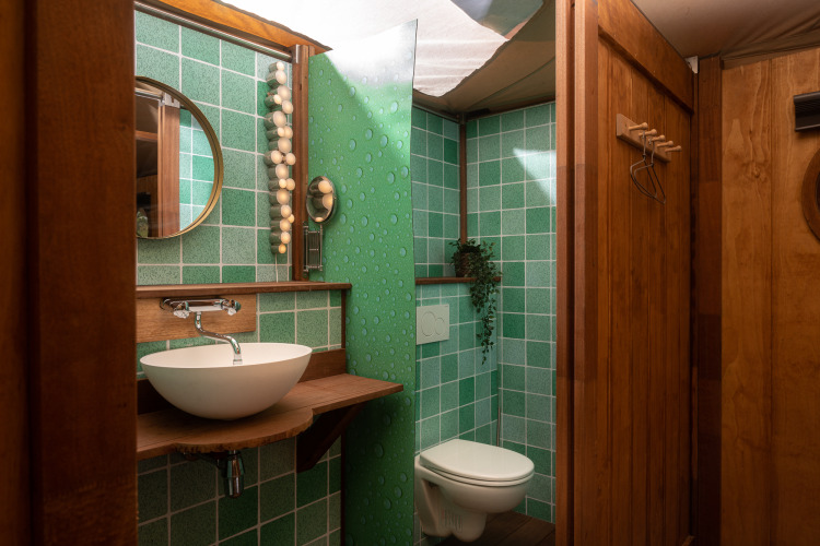 Baño en la Dream suite del safari tent en Holiday Park Mölke, Países Bajos, con azulejos verdes y madera.