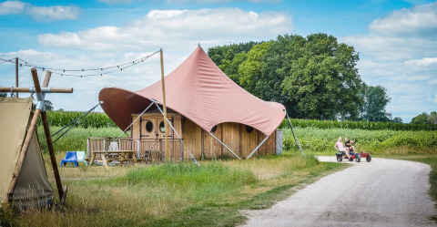 Safaritent Dream suite in vakantiepark Mölke, Nederland, met kinderen op een trapwagen op het pad.