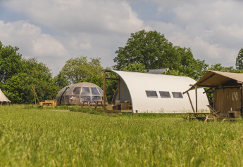 Riverdome en sanitaire blok bij Holiday Park Mölke in Nederland, te midden van groene weiden en bomen.