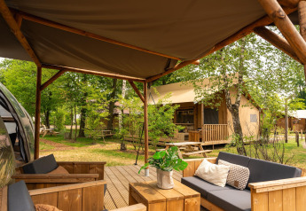 Udendørs opholdsområde ved Riverdome lodge med moderne møbler og udsigt til hytter i Holiday Park Mölke.