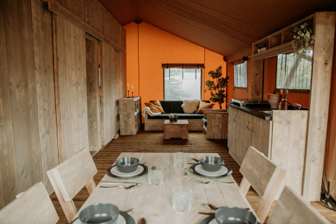 Interior de una tienda safari de lujo con mobiliario de madera, comedor, sala y cocina pequeña.