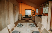 Interior de una tienda safari de lujo con mobiliario de madera, comedor, sala y cocina pequeña.