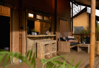 Houten terras met bar en zithoek bij safaritent 'the bartender' op Vakantiepark Mölke in Nederland.