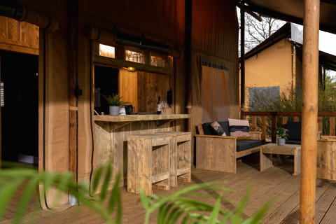 Houten terras met bar en salon bij safaritent 'the bartender' op Vakantiepark Mölke, Nederland.