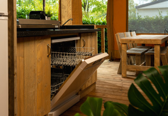 Cocina en tienda safari con lavavajillas y mesa de comedor en Holiday Park Mölke, Países Bajos.