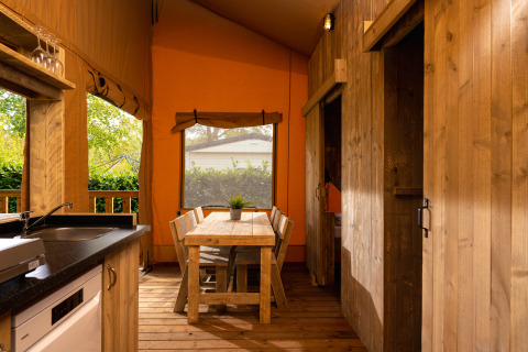 Interior view of Safari tent 'the bartender' with wooden furniture and kitchen at Holiday Park Mölke, Netherlands.