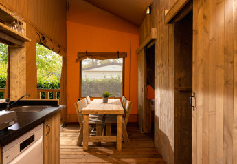 Vista interna della tenda safari 'the bartender' con mobili in legno e cucina a Holiday Park Mölke, Paesi Bassi.
