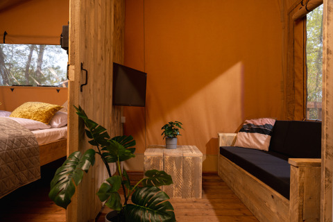 Interieur van safaritent 'the bartender' met houten meubels en planten in Holiday Park Mölke, Nederland.