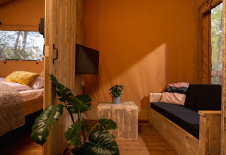 Interieur van safaritent 'the bartender' met houten meubels en planten bij Holiday Park Mölke, Nederland.