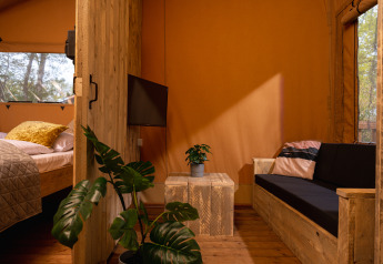 Interieur van safaritent 'the bartender' met houten meubels en planten bij Holiday Park Mölke, Nederland.